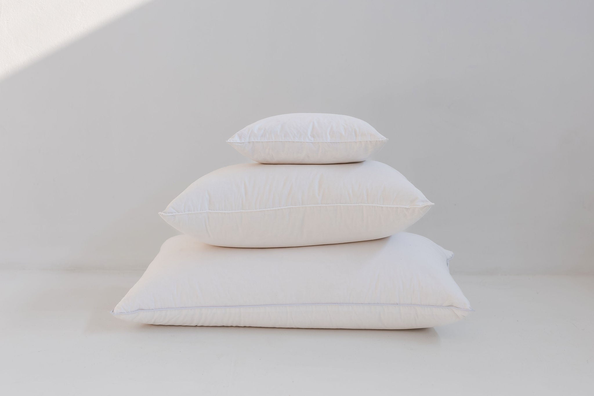 Stack of white pillows on a light gray background